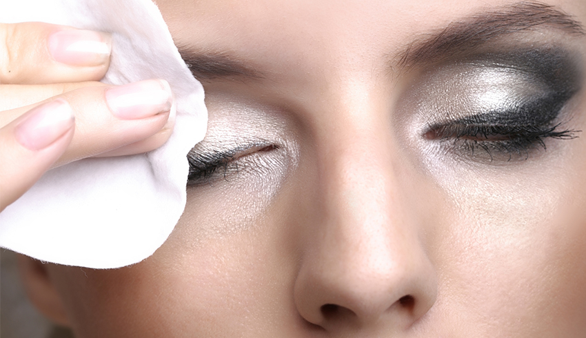 A woman wiping away eye makeup with a makeup wipe